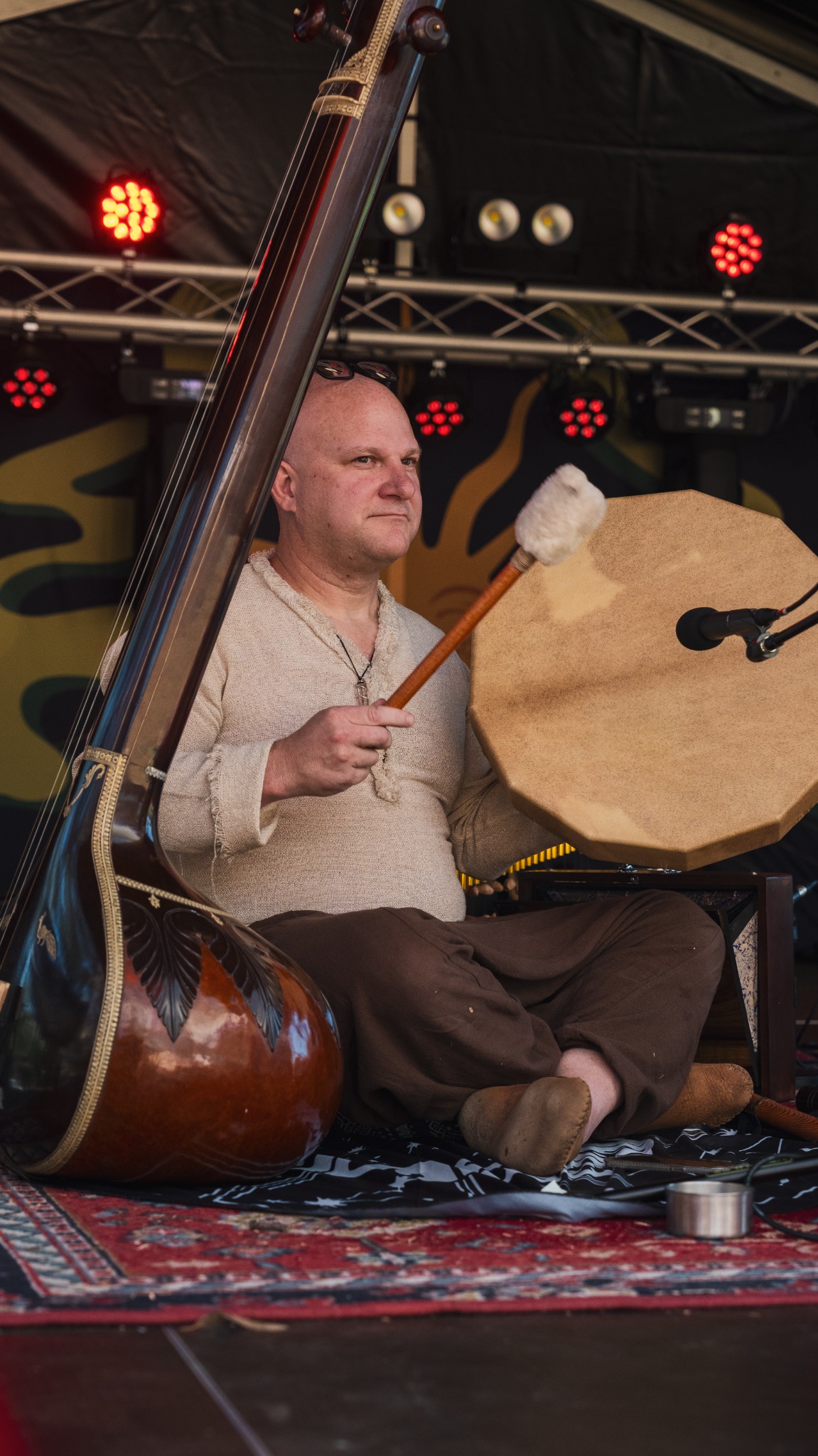 Musician playing a frame drum beside a string instrument